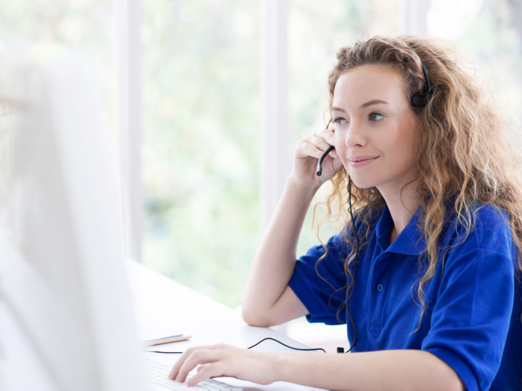 woman sitting at a computer wearing a headset